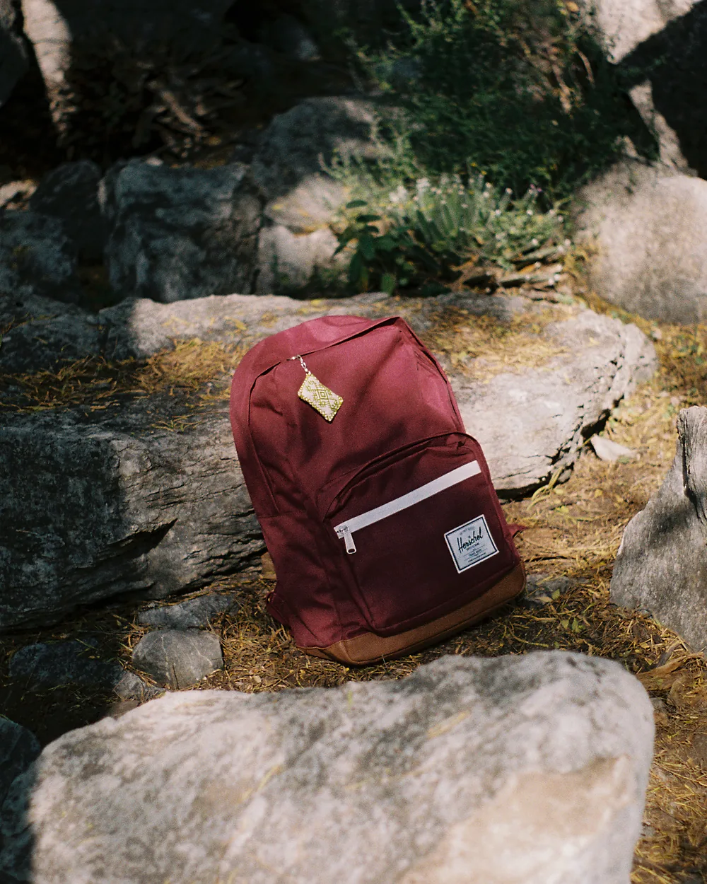A travel backpack resting on rocks outdoors