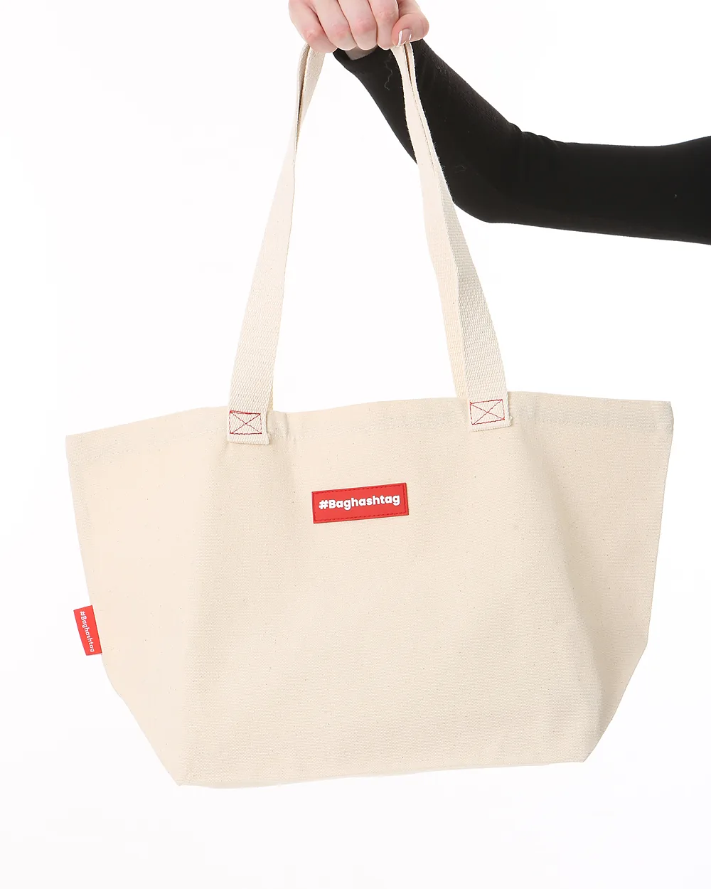 A plain tote bag held up by its handles against a white background