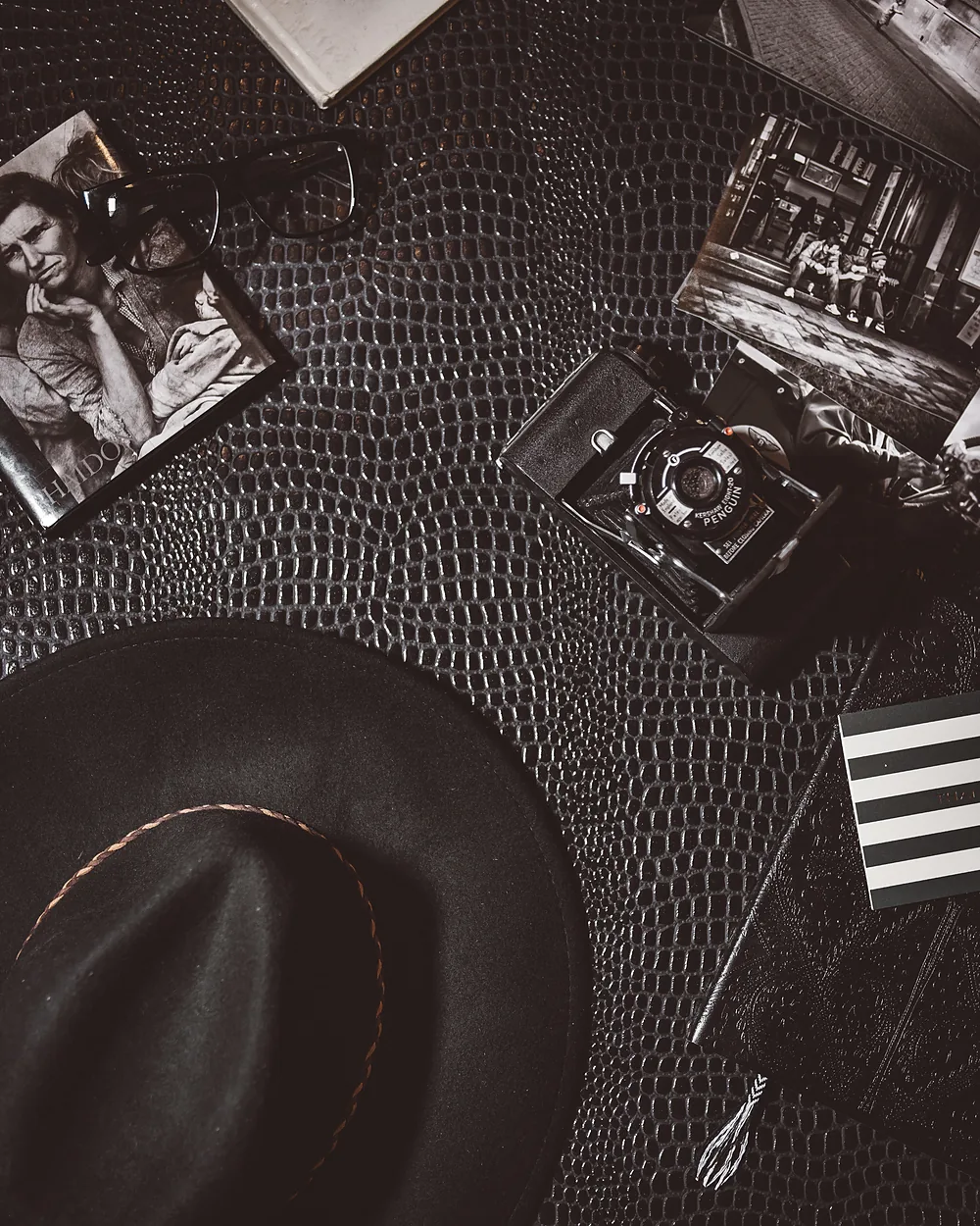 A felt hat and vintage accessories resting on a grained leather surface
