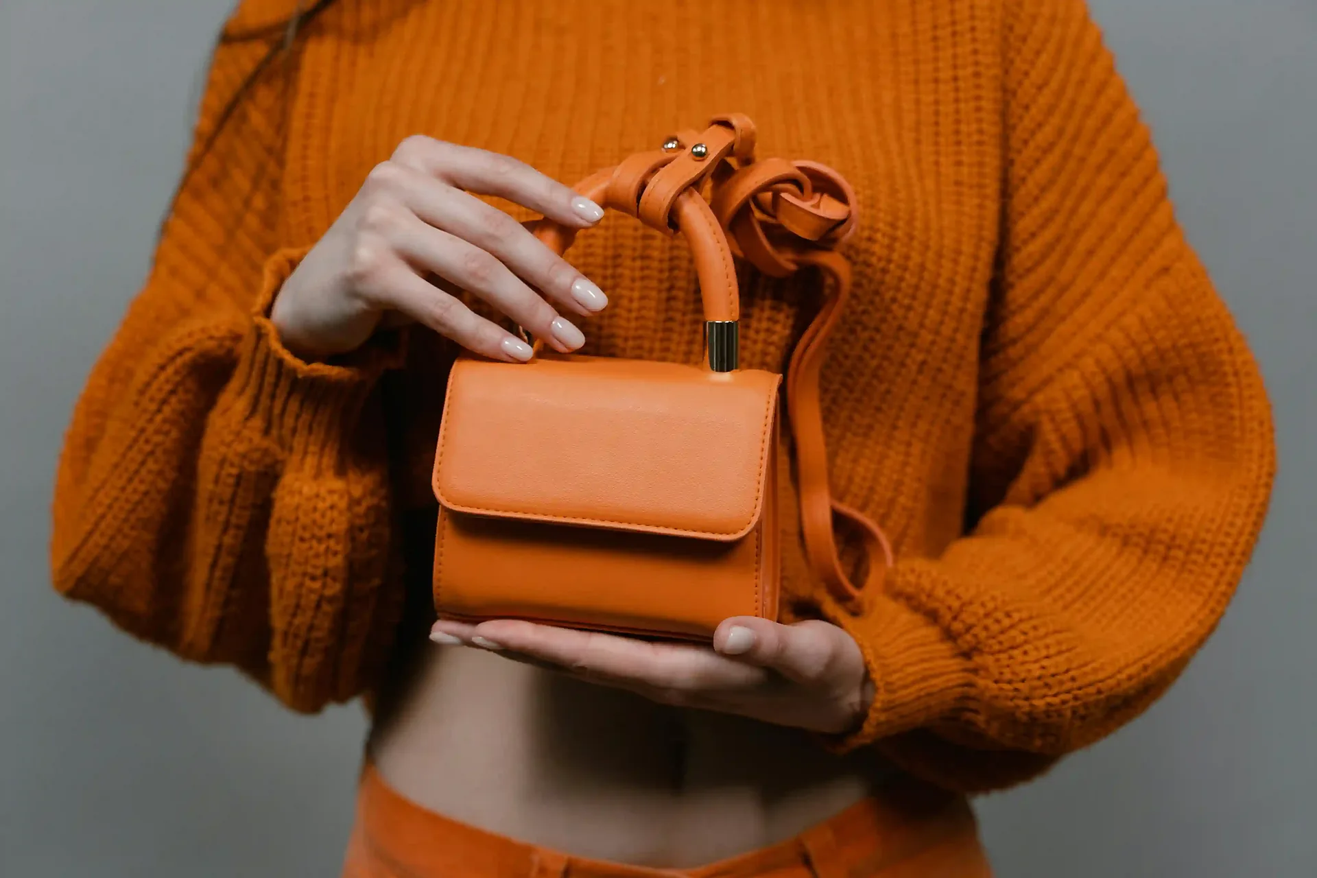 A tan leather crossbody bag held in both hands