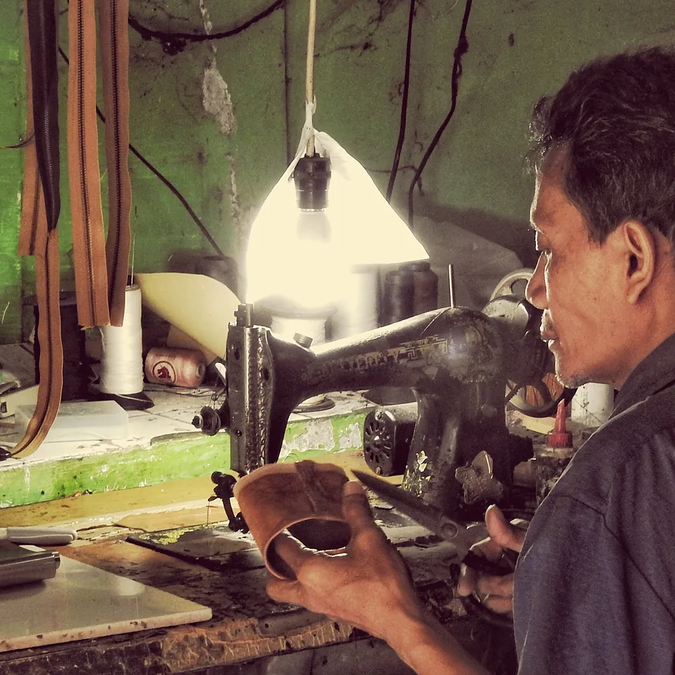A machinist stitching leather at the workshop machine
