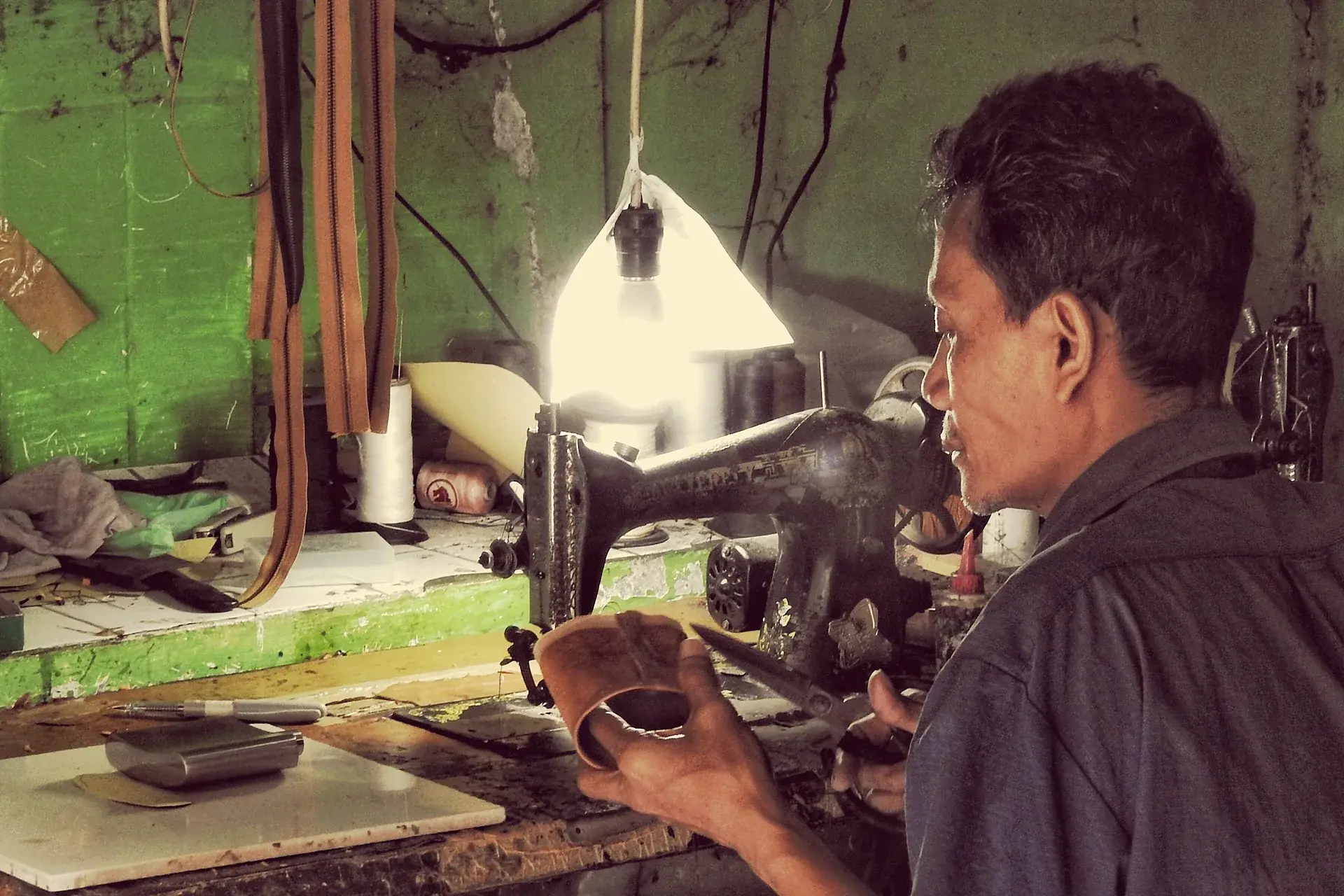 A machinist stitching leather at a workshop sewing machine