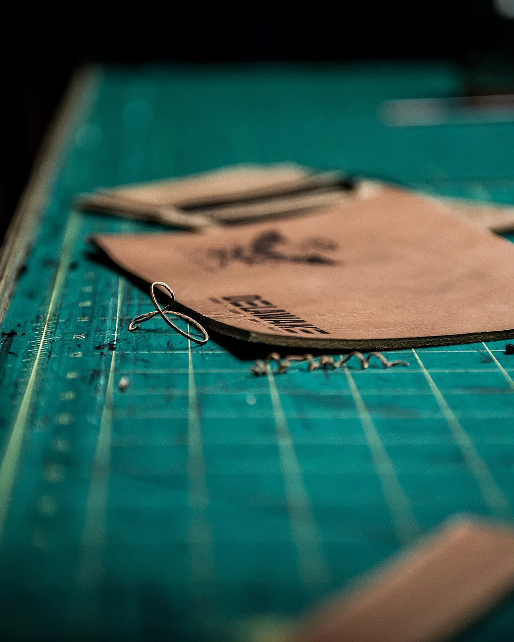 A paper pattern and leather panel on the cutting mat during design work