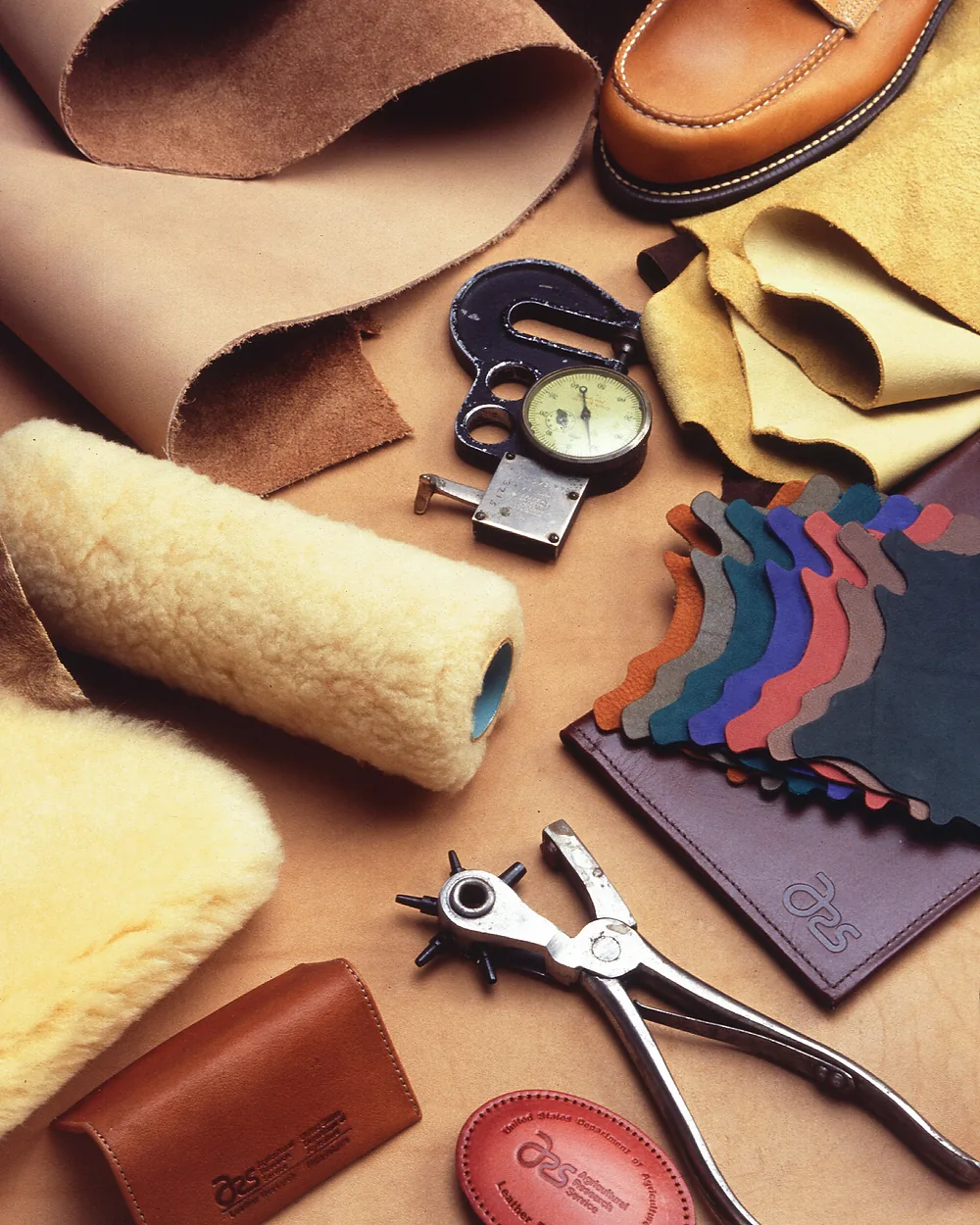 Leathercraft hand tools, punches and hide swatches arranged on a bench