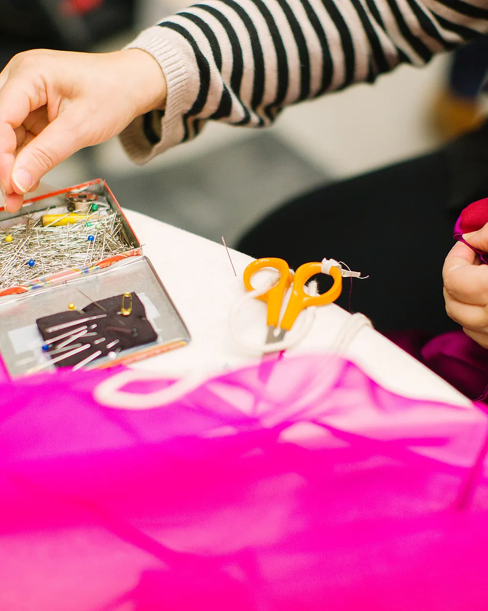A pair of hands stitching at a workshop table