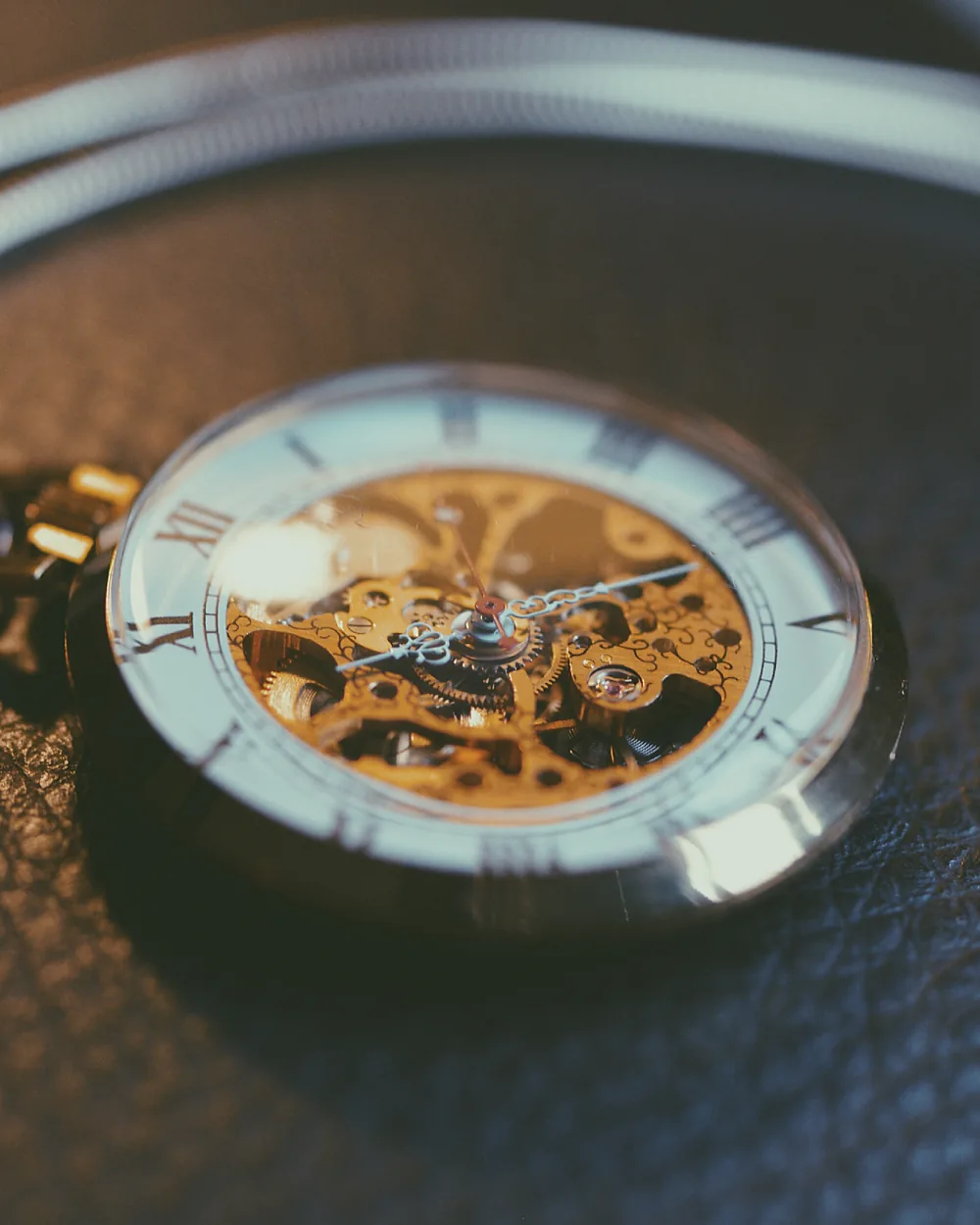 A pocket watch resting on a grained leather surface