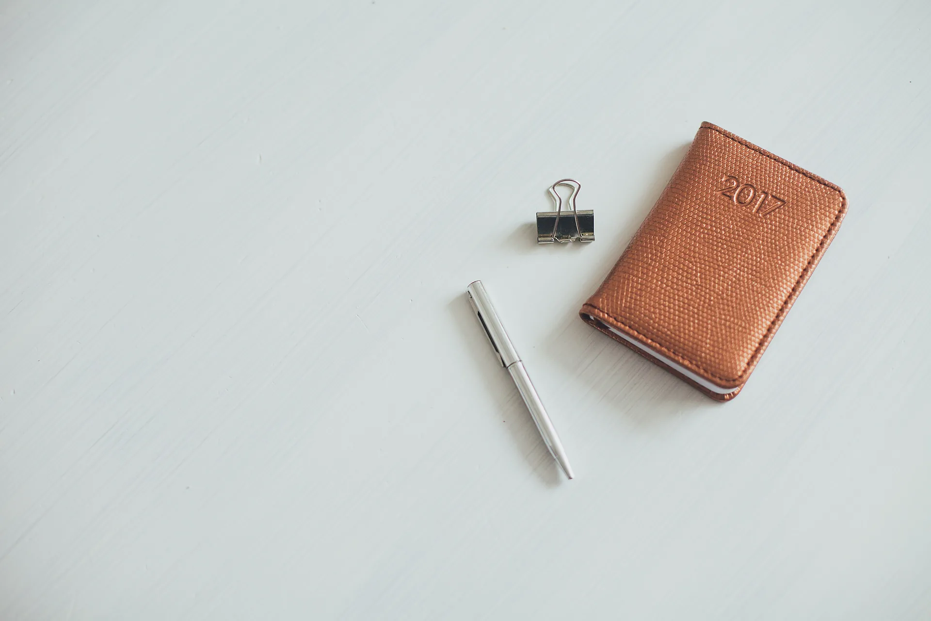 A tan leather card wallet with a blind-stamped mark on its cover