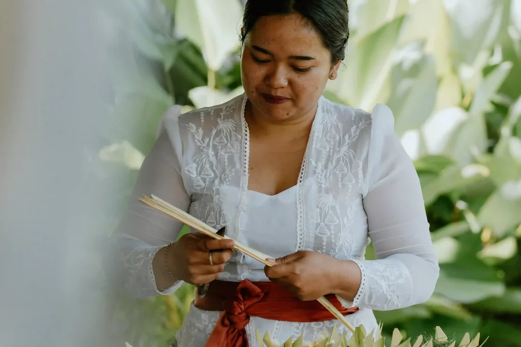 Balinese woman handcrafting a traditional offering